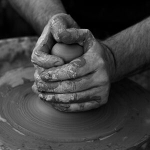 grayscale photography of person's hand making pot